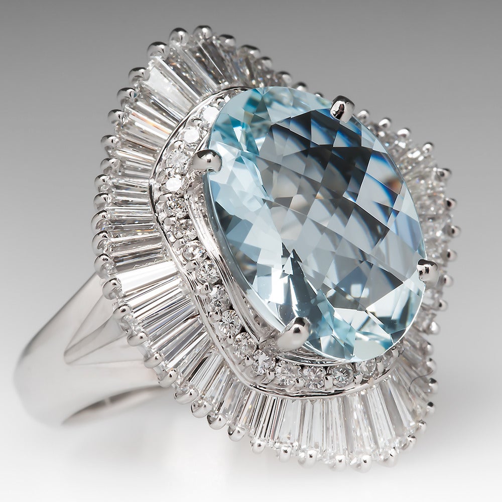 This stunning ballerina cocktail ring features a large natural aquamarine center stone surrounded by a halo of baguette cut natural diamonds. There is also an inner halo of round brilliant diamonds between the aquamarine and the baguettes. All the