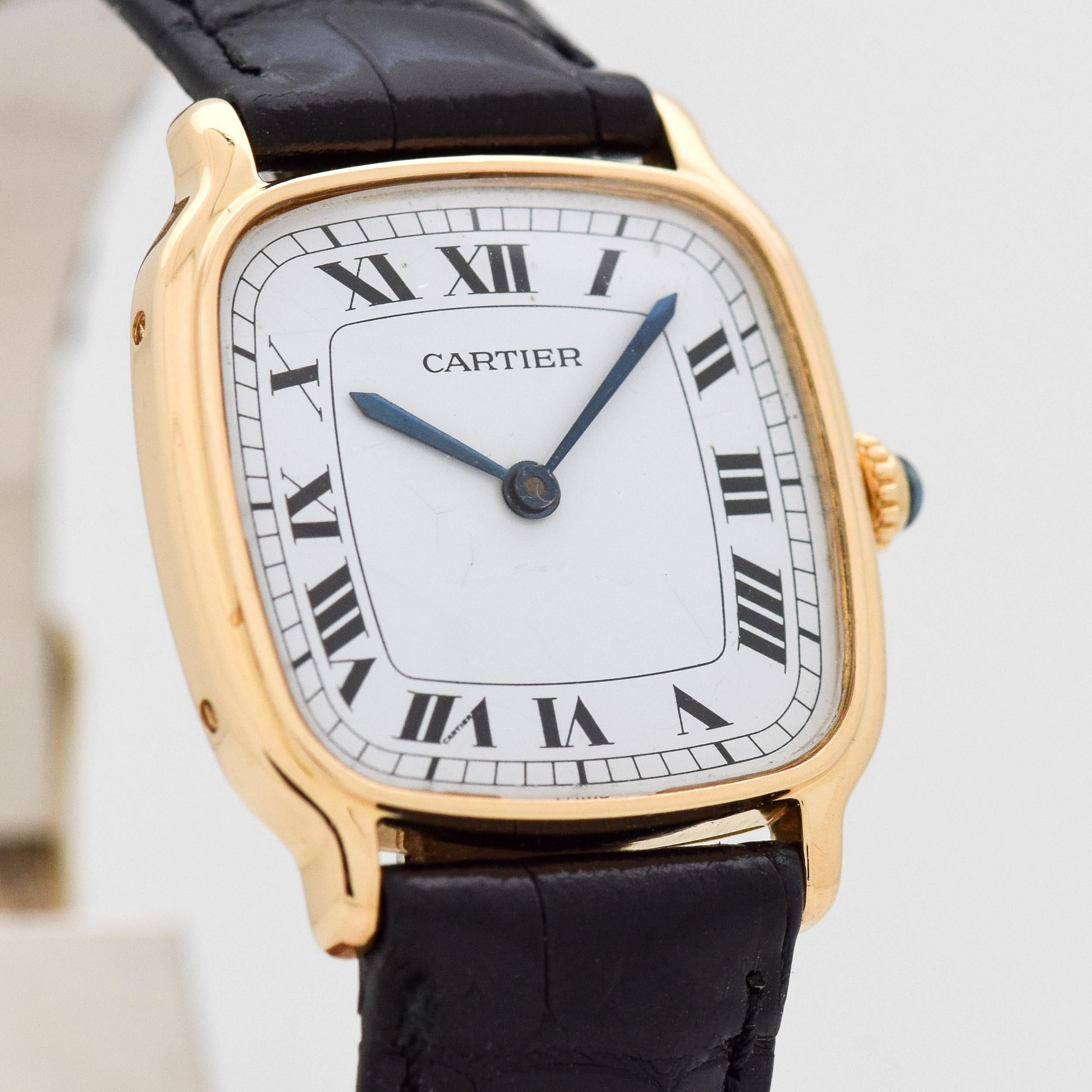 2010's Cartier 18k Yellow Gold Cushion Shape watch with Original White Dial with Black Roman Numerals. 26mm x 30mm lug to lug (1.02 in. x 1.18 in.) - 17 jewel, manual caliber ETA movement. 100% Genuine Alligator Glossy Black Strap. Suitable for a