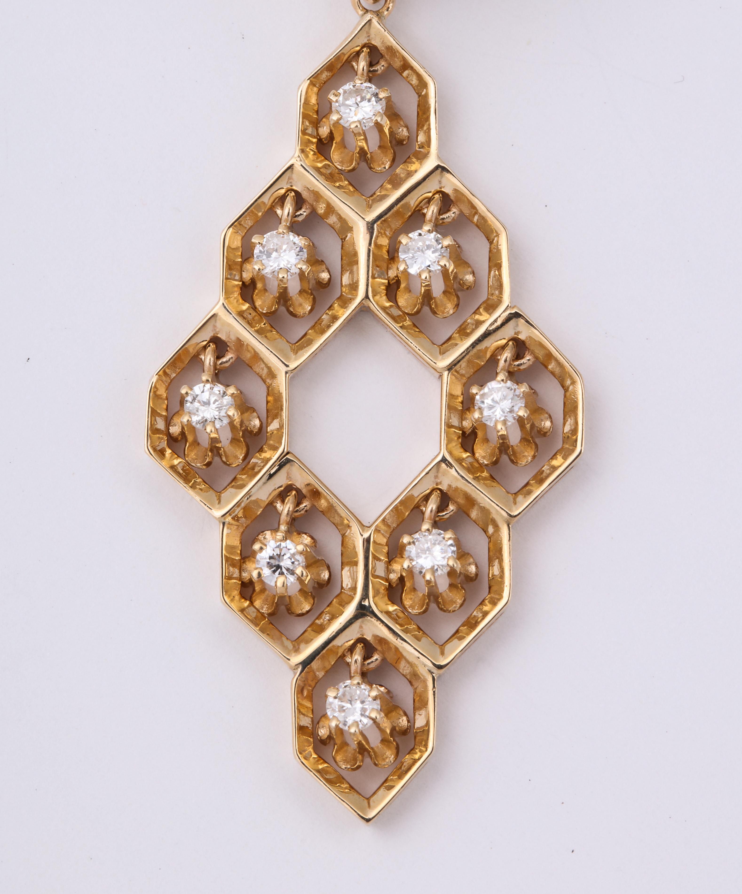 A pair of flirtatious dangle earrings in 14 kt gold in a honeycomb form. Free floating  diamond in a floral form  dangle from the center of the 18 hexagons.  