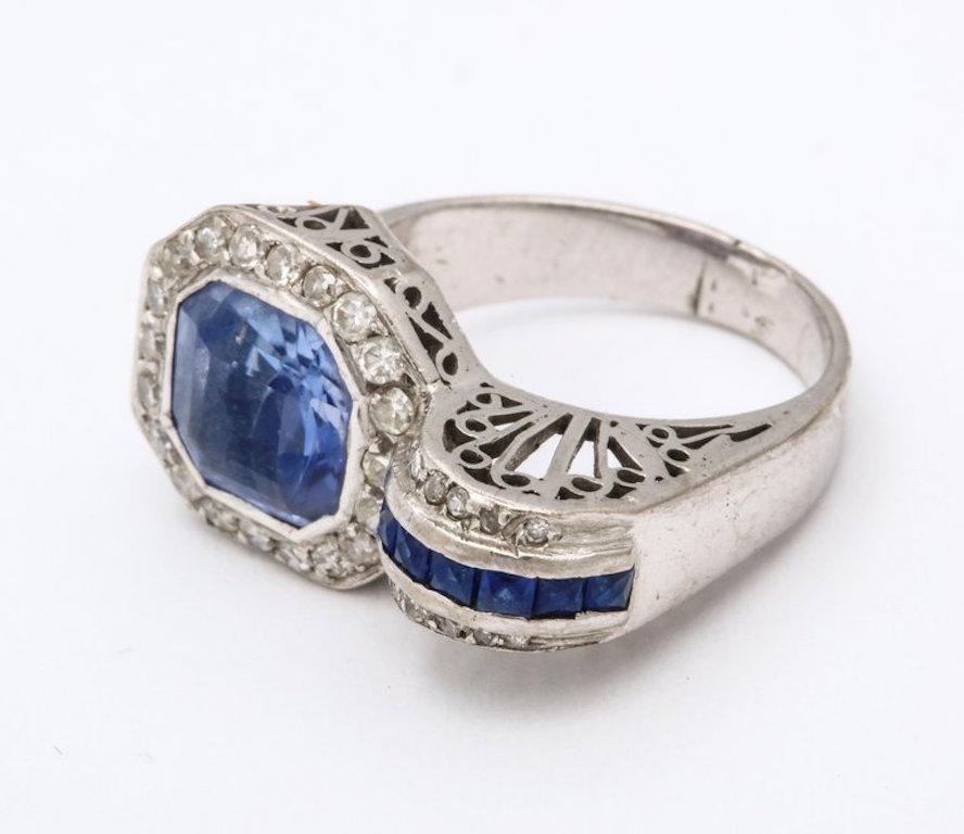 A classic Art Deco platinum ring with diamonds surrounding a sapphire and a band of smaller sapphires.