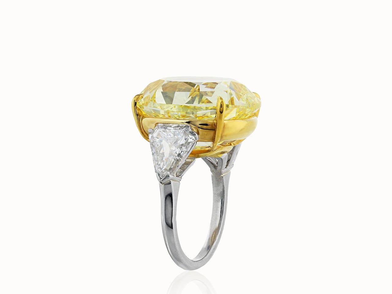 Platinum and 18 karat yellow gold custom made 3 stone ring consisting of 1 cushion cut canary diamond weighing 28.02 carats having a color and clarity of FIY/VS2 with GIA certificate, the center stone is flanked by 1 brilliant cut shield shaped