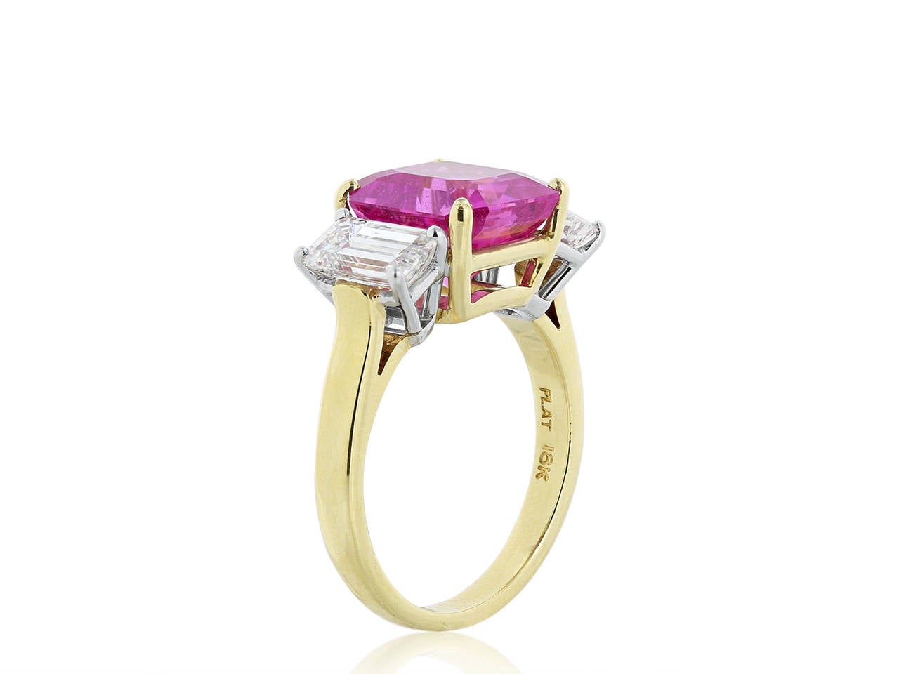 18 karat yellow gold and platinum three stone ring consisting of one radiant cut No Heat pink sapphire, weighing 6.13 carats with GIA report number 1162715810, flanked by 2 emerald cut diamonds having a total weight of 2.06 carats, one weighing 1.01