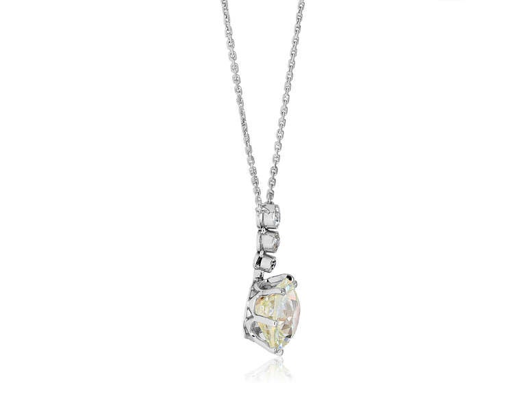Platinum vintage 7 prong pendant consisting of 1 Old European cut cut diamond weighing 7.01 carats, having a color and clarity of J/VVS2 set with 3 bezel set Old European cut diamond accents.