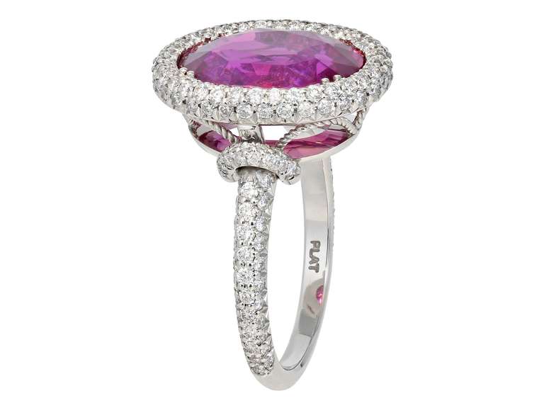 Platinum cluster ring consisting of 1 oval shaped pink sapphire weighing 6.47 carats set with .85 carats total weight of round brilliant cut diamonds surrounding the center stone and going down the shoulders and a filigree under  gallery.