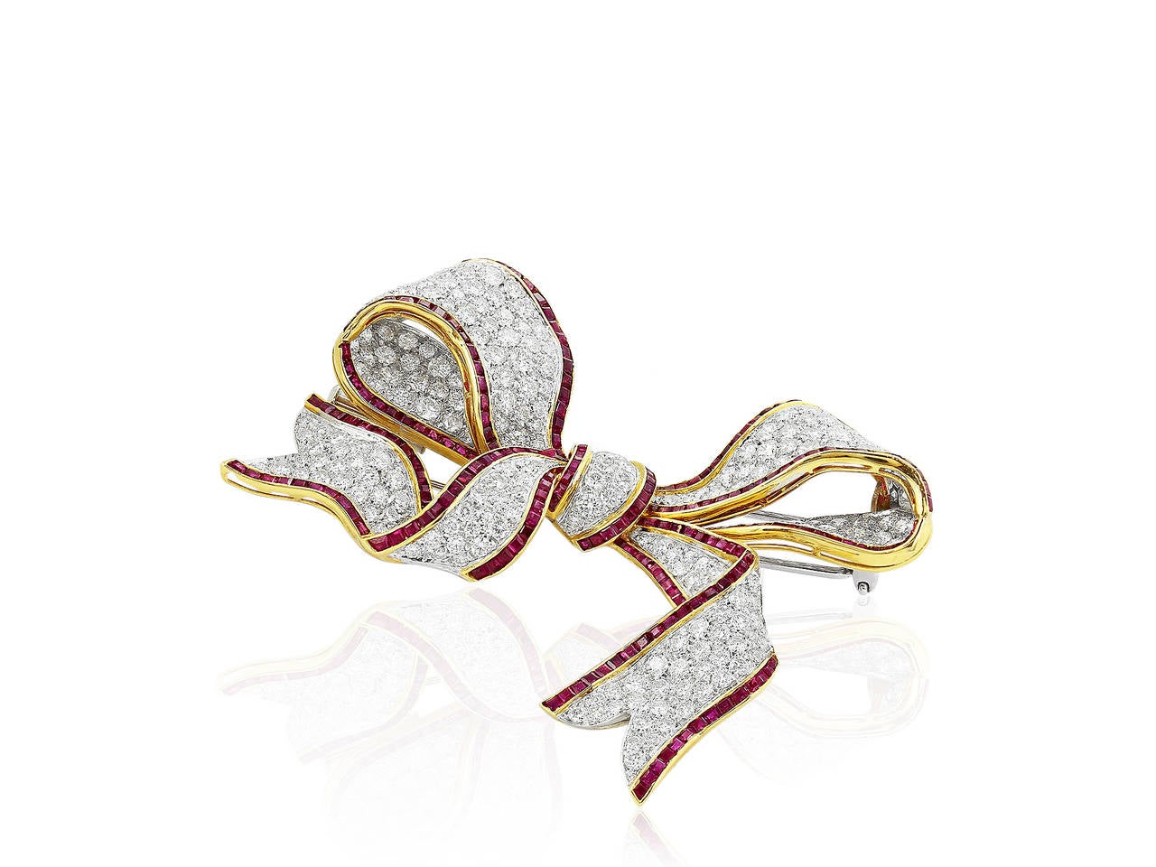 Two tone 18 karat yellow and white gold bow pin consisting of approximately 8.00 carats total weight set with custom cut ruby accents.