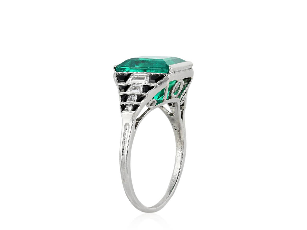 Platinum Art Deco ring consisting of 1 Colombian emerald weighing 4.36 carats, the emerald is flanked by step cut trapezoid diamond and custom cut onyx and a filigree undergallery.