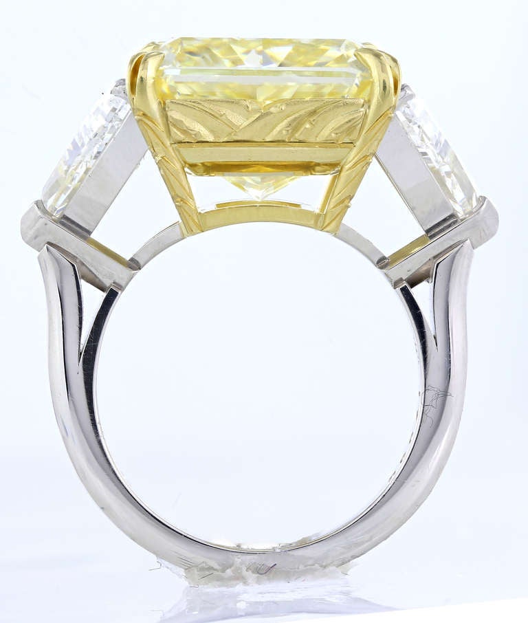 Magnificent and rare platinum & 18 karat yellow gold 3 stone ring consisting of 1 radiant cut canary diamond weighing 15.15 carats Fancy Yellow VS2 quality diamond set in an 18k white and yellow gold mounting flanked by two trillian cut diamonds