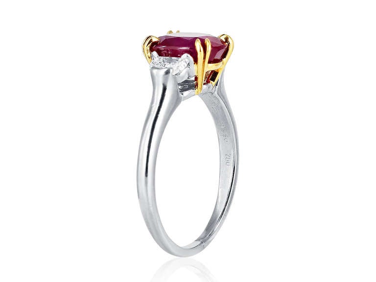 Platinum and 18 karat yellow gold three stone ring consisting of one oval shaped Burma ruby weighing 3.29 carats, ruby set in double prongs, the center stone is flanked by 2 brilliant cut half moon diamonds, signed Harry Winston.