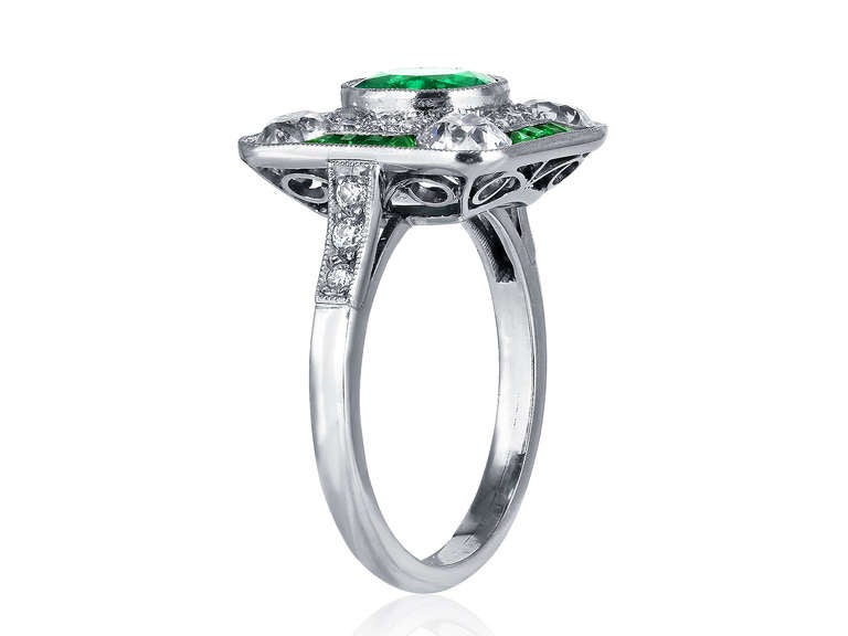 Platinum Emerald and diamond ring consisting of one round old mine emerald weighing 1.30 carats set with approximately 1.00 carats total weight of Old European cut diamonds in a beaded mounting.
