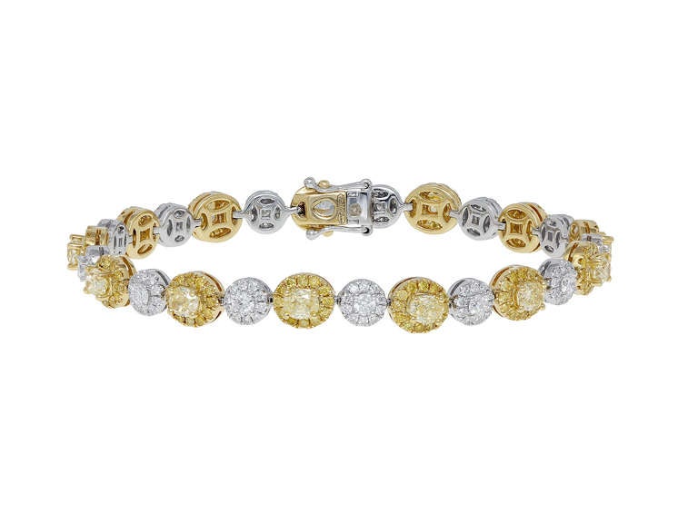 Two tone 18 karat yellow and white gold flexible
bracelet consisting of 13 oval shaped canary
diamonds having a total weight 3.84, set with 1.54
carats total weight of full cut canary diamonds, and
2.15 carats total weight of colorless round