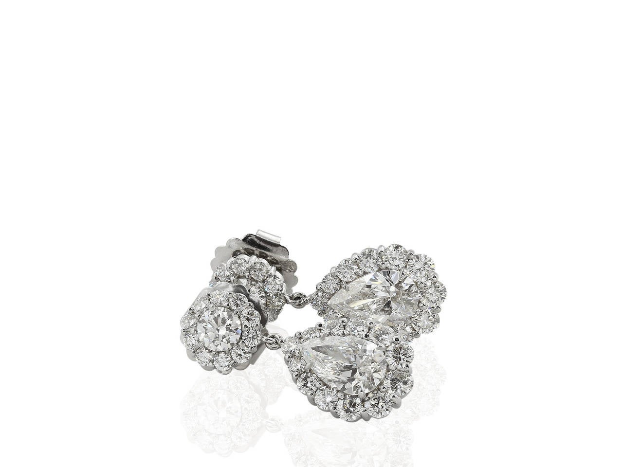 Custom made 18 karat white gold cluster style drop earrings featuring 1 pear cut diamond drop weighing 1.50 carats, measuring 9.78 - x 6.29 x 3.88 mm, having a color and clarity of G/SI1 and GIA report 2147897142, a second pear cut diamond drop