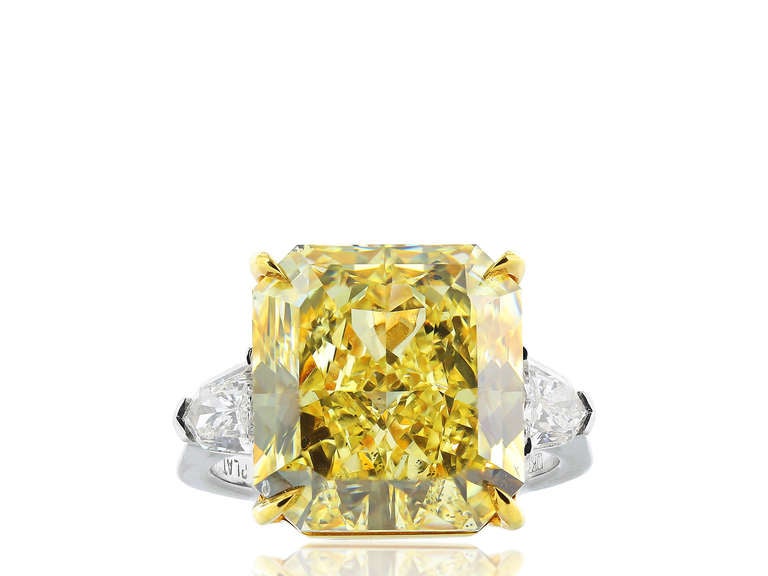Rare Canary diamond 3 stone ring. Consisting of 1 radiant cut fancy yellow canary diamond weighing 12.03 carats having a color and clarity of FY/SI-2 carats with GIA 5151588045.  The center stone is flanked by 2 brilliant cut shield diamonds having