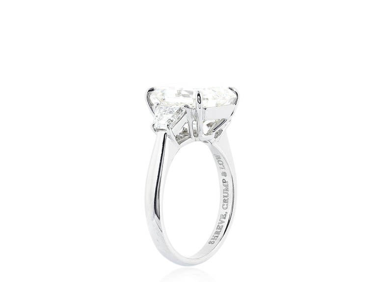 Platinum custom made 3 stone ring consisting of 1 emerald cut diamond weighing 5.90 carats having a color and clarity of J/SI1, measuring 11.13 x 9.50 x 6.27mm with GIA certificate #1156895684, the center stone is flanked by 2 step cut trapezoid