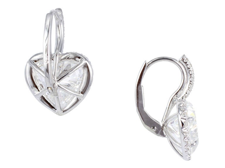 18 karat white gold earrings consisting of two heart shape diamond weighing 1.87 and 1.97 carats having a color and clarity of F/SI2 respectively, the center diamonds are set with 62 full cut diamonds having a total weight of .42 carats.