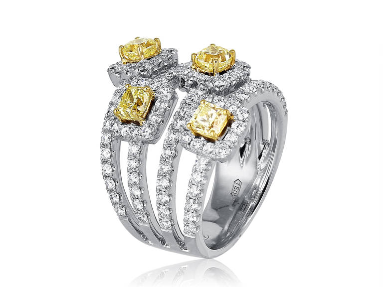 18 karat white and yellow gold ring consisting of 4 radiant cut canary yellow diamonds having a total weight of 1.39 carats set with 1.80 carats total weight of colorless round brilliant cut diamonds.