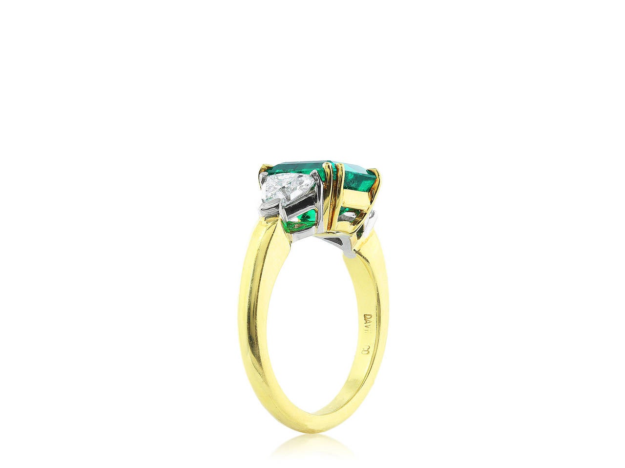 Platinum and 18 karat yellow gold three stone ring consisting of one emerald cut natural emerald weighing 2.47 carats flanked by two trilliant cut diamonds having a total weight of 1.02 carats.