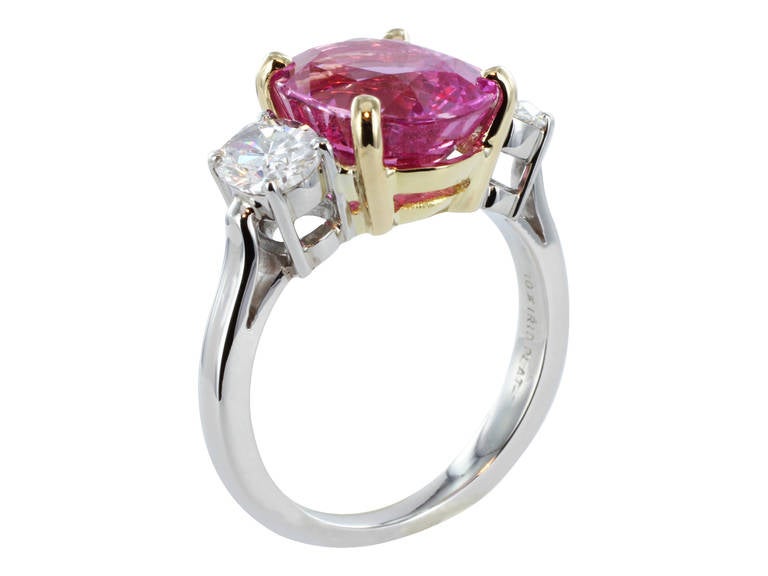 Platinum and 18 karat yellow gold custom made 3 stone ring consisting of 1 oval shaped pink sapphire weighing 6.22 carats, the center stone is flanked by 2 oval brilliant diamond having a total weight of 1.85 carats.