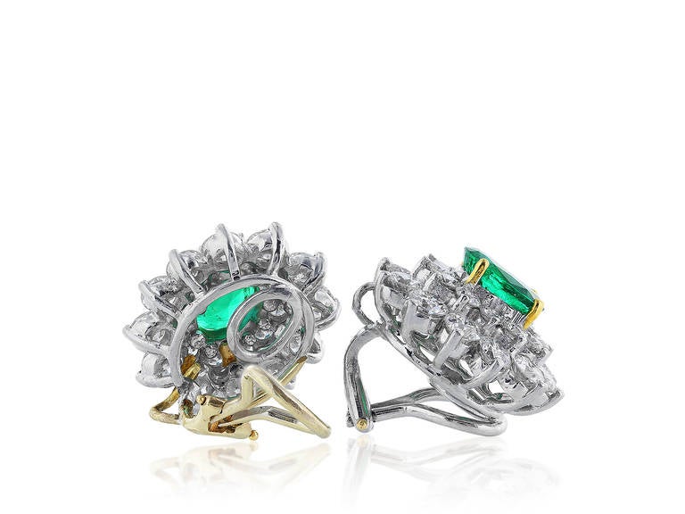 Platinum cluster earrings consisting of 2 oval shaped emeralds having a total weight of approximately 2.50 carats set with approximately 5.00 carats total weight of round brilliant cut diamonds.