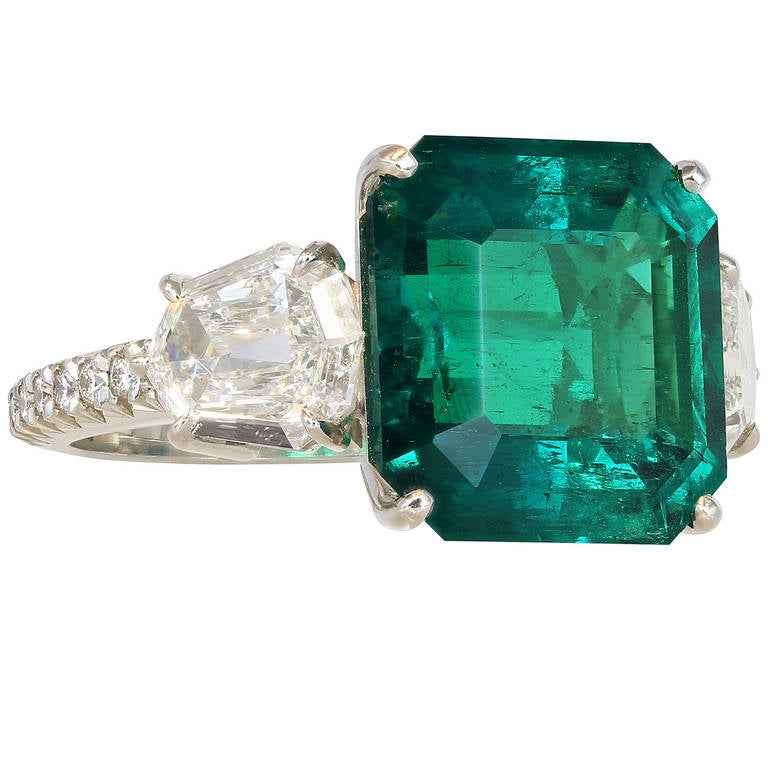 Platinum custom made 3 stone ring consisting of 1 square emerald cut Colombian emerald weighing 5.48 carats, the center stone is flanked by 2 step cut kite shaped diamond with full cut diamonds going down the shoulders, the total diamond weight is
