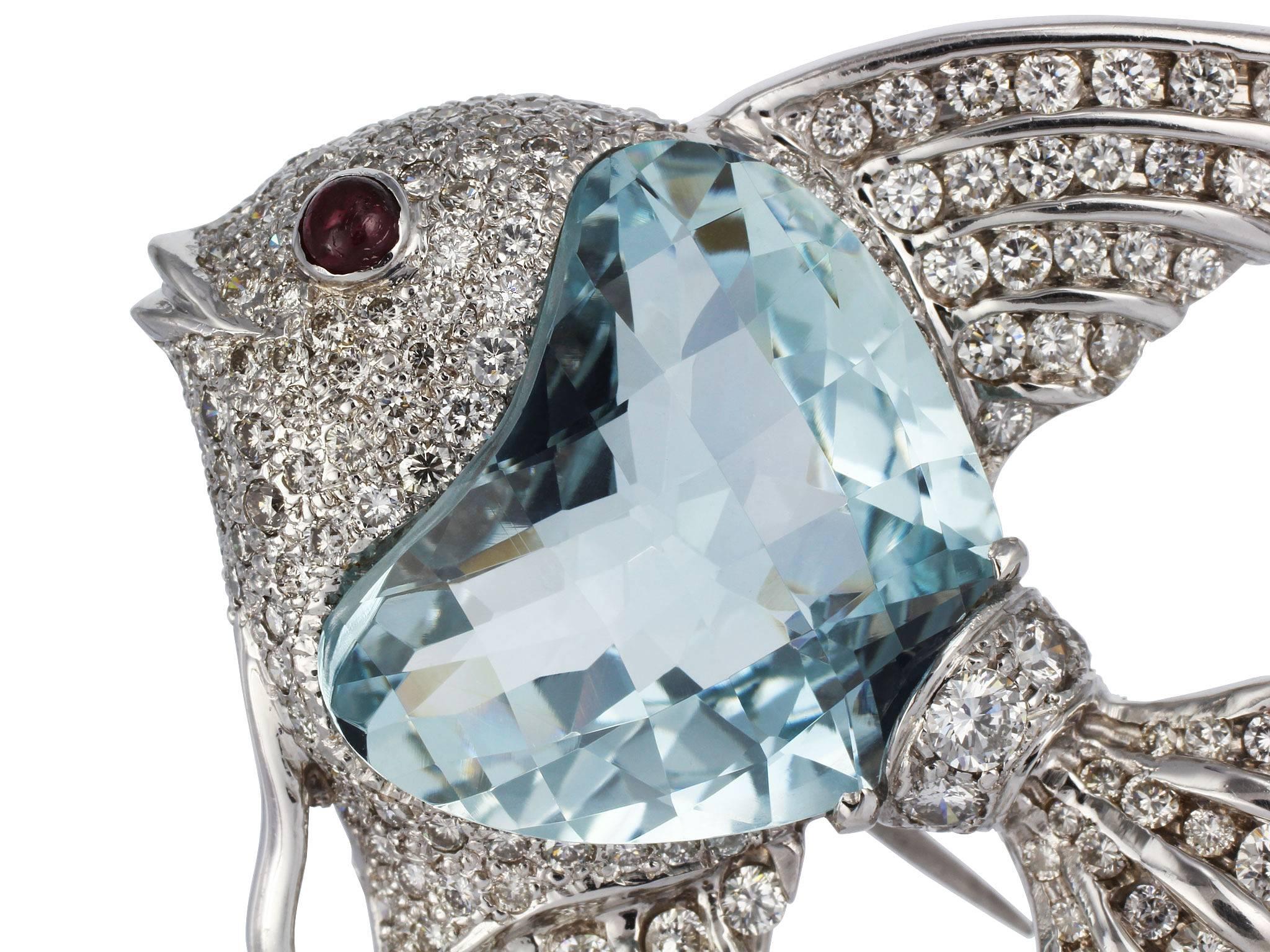 18 karat white gold angelfish pin consisting of of one fantasy cut aquamarine weighing approximately 24.00 carats, channel and pave set round brilliant cut diamonds having an approximate total weight of 8.00 carats and a single cabochon ruby eye. 