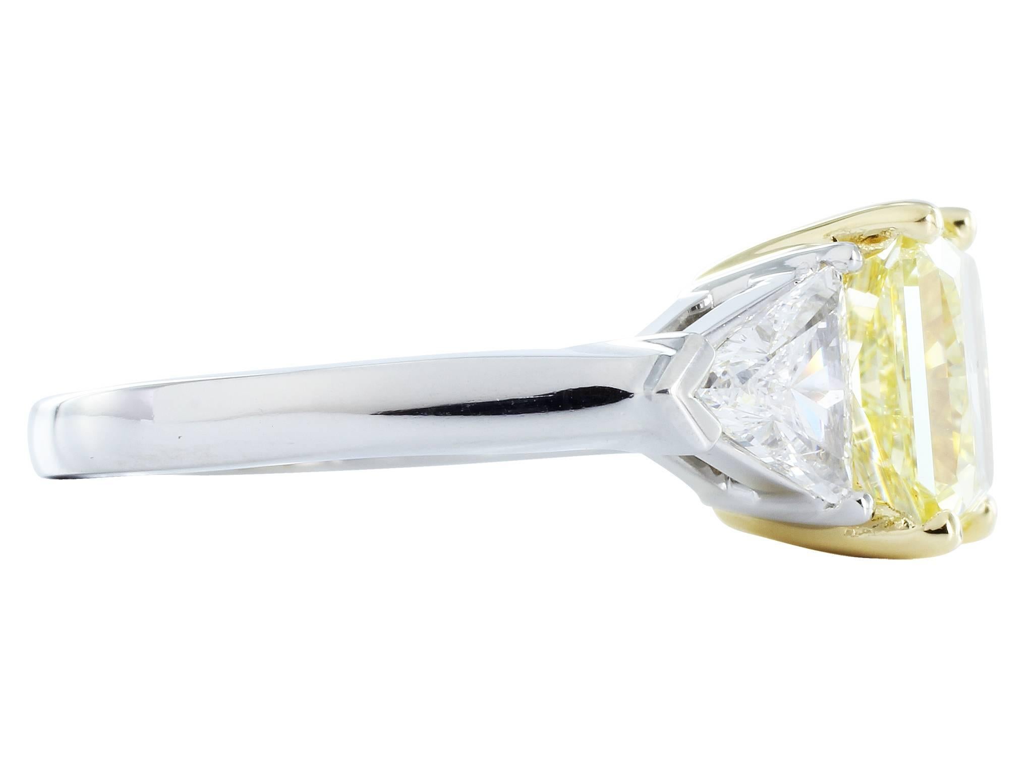 18 karat yellow gold and platinum 3 stone ring. The ring features 1 radiant cut Natural Fancy Intense yellow diamond, weighing 2.50 carats, measuring 7.91 x 7.42 x 4.54 mm with GIA colored diamond report 1122830753. The center stone is flanked by