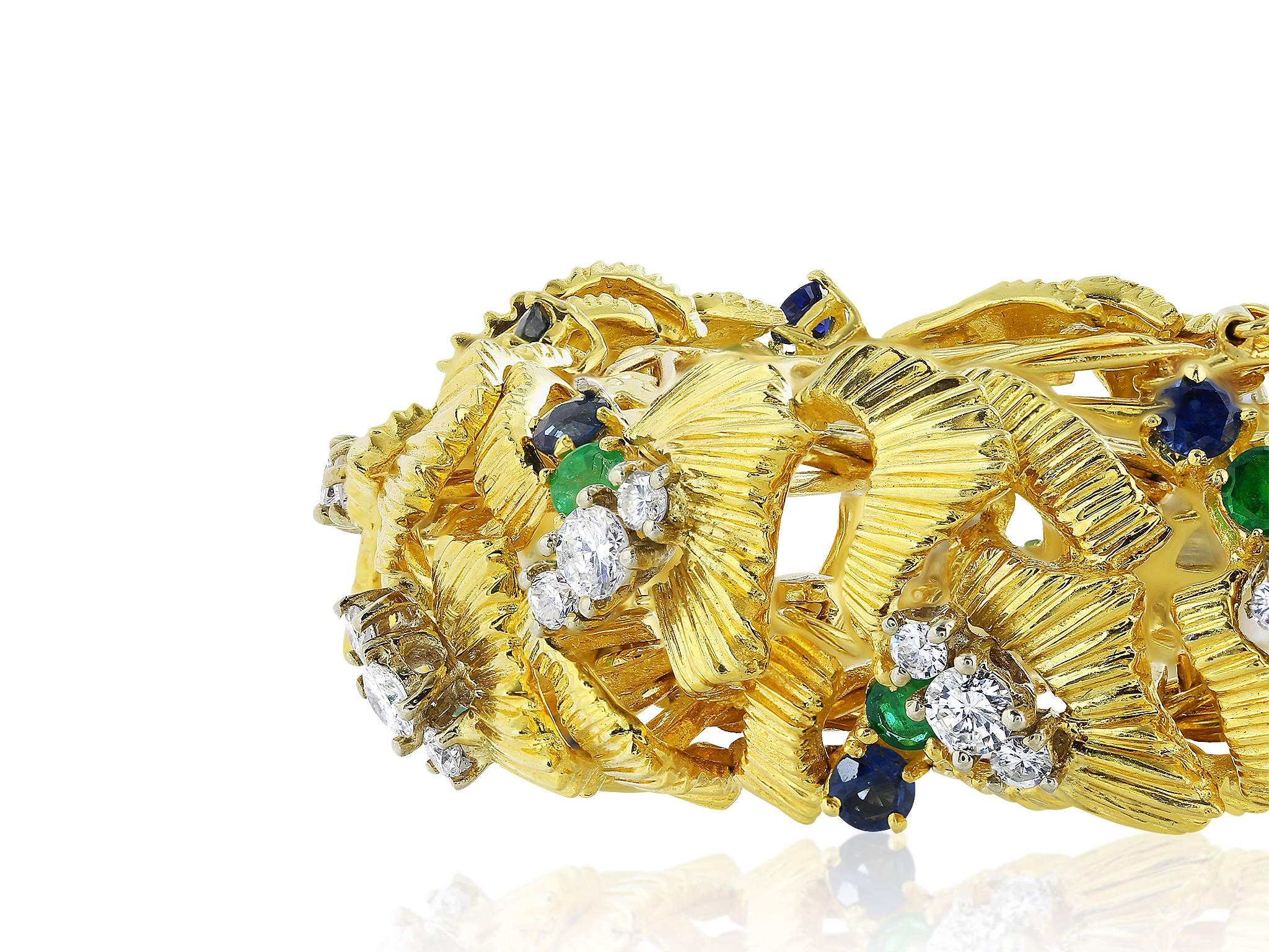 18 karat yellow gold semi flexible open work estate bracelet with full cut diamond, sapphire and emerald accents.
