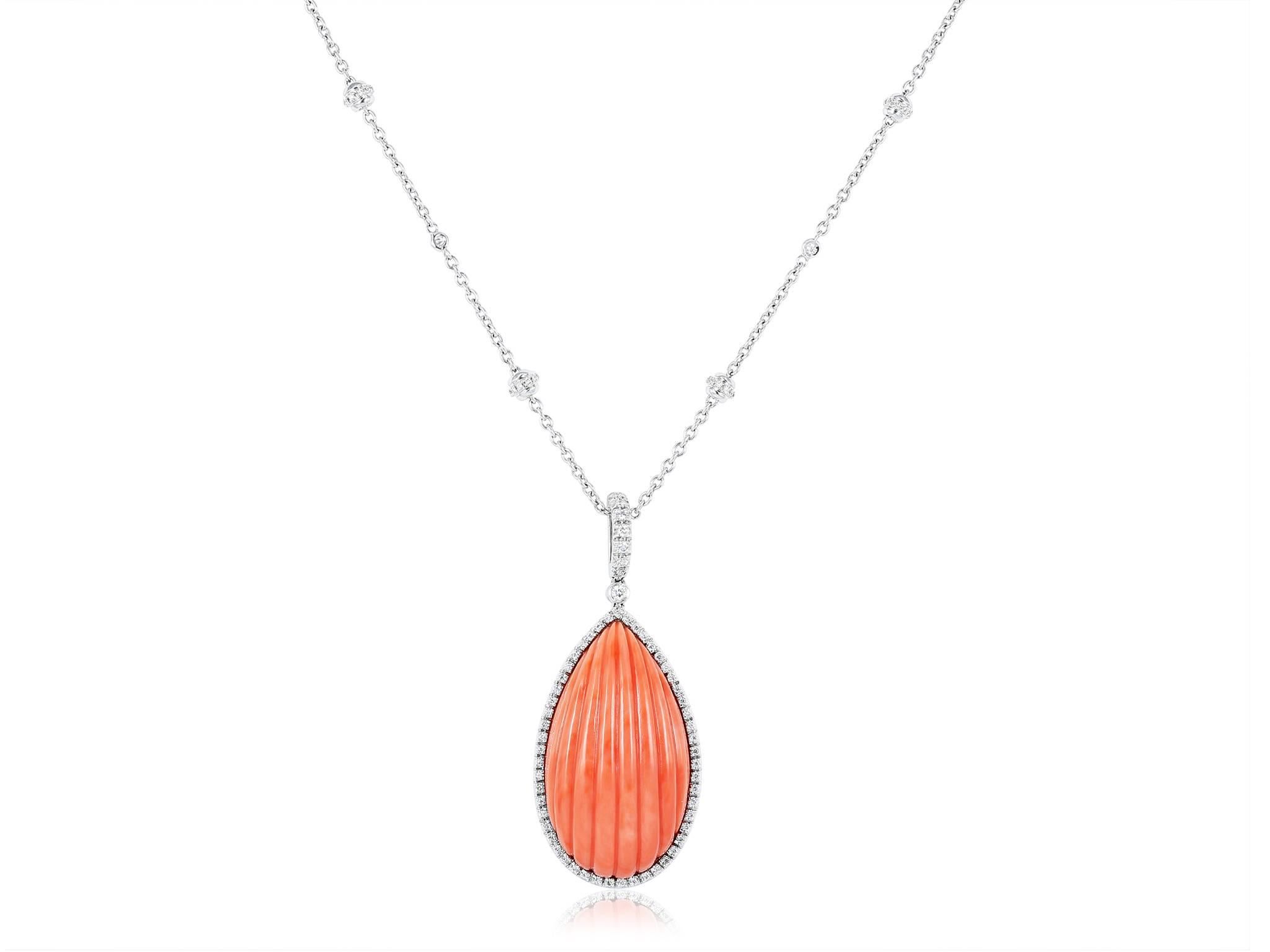 18 karat white gold pendant consisting of 1 tear drop shaped carved coral piece set surrounded by full cut diamond accents, the pendant hangs from an opera length by the yard style necklace set with diamond accents.