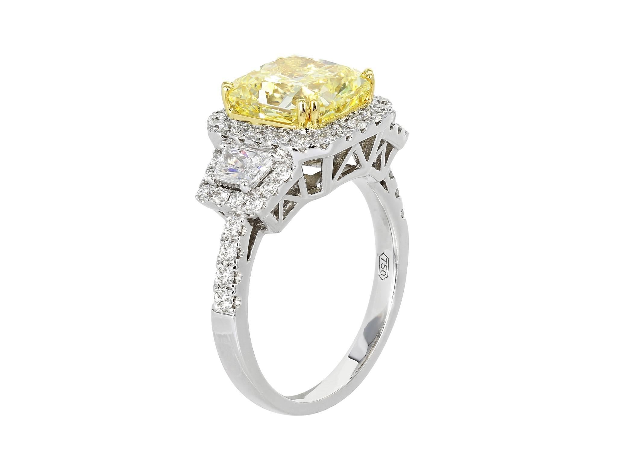Platinum & 18 karat yellow gold 3 stone halo style ring consisting of 1 radiant cut natural Fancy Yellow diamond weighing 3.77 carats with GIA certificate #1152160915,  flanked by 2 trapezoid cut white diamonds having a total weight of .52 carats
