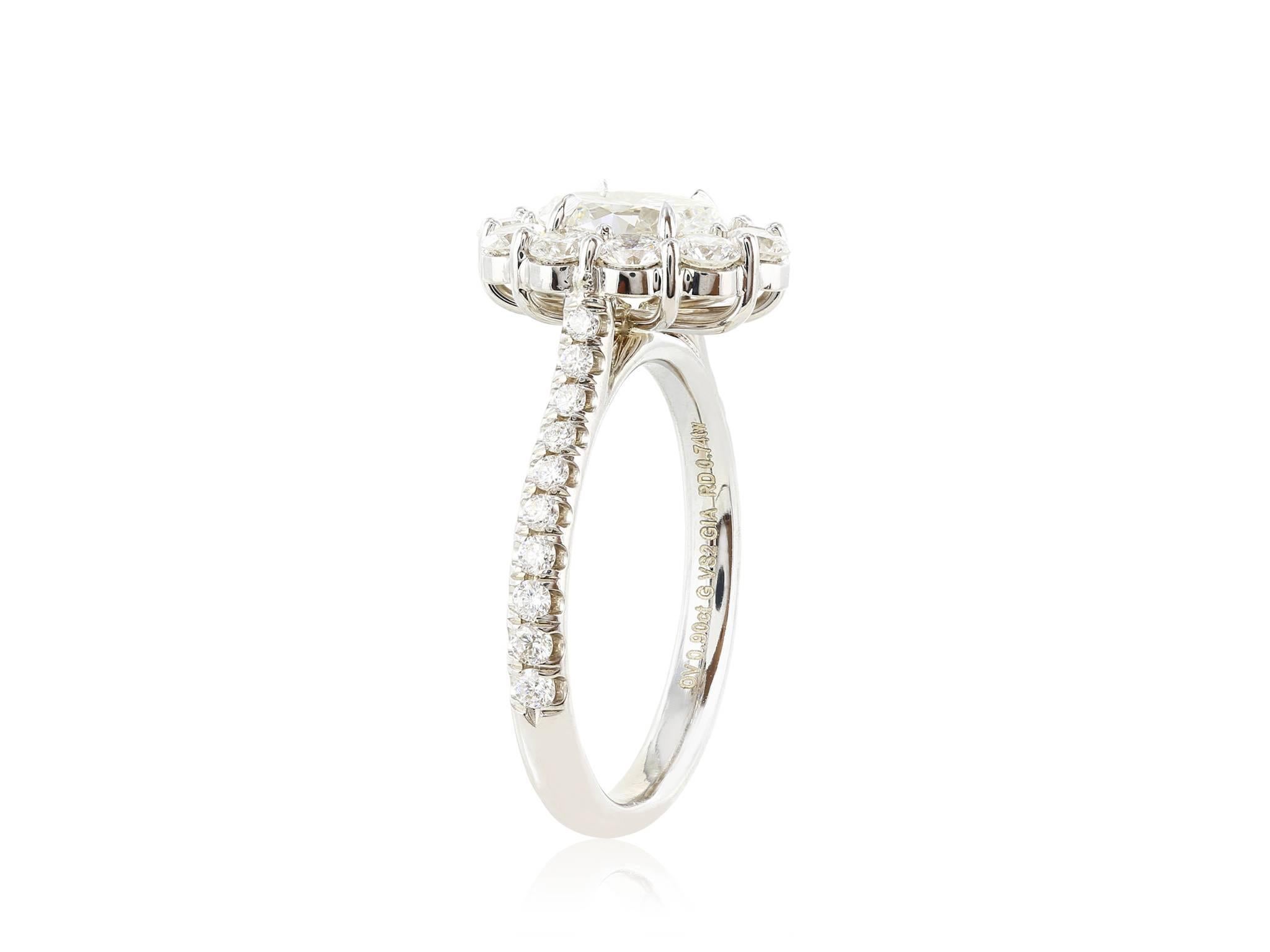 18 karat white gold ring consisitng of 1 oval diamond weighing .90 carats with a color and clarity of G VS2 respectively with GIA report # 2217696744, 7.55 x 5.40 x 3.41mm and surrounded by 10 rounds diamonds weighing .74 carats and full cut