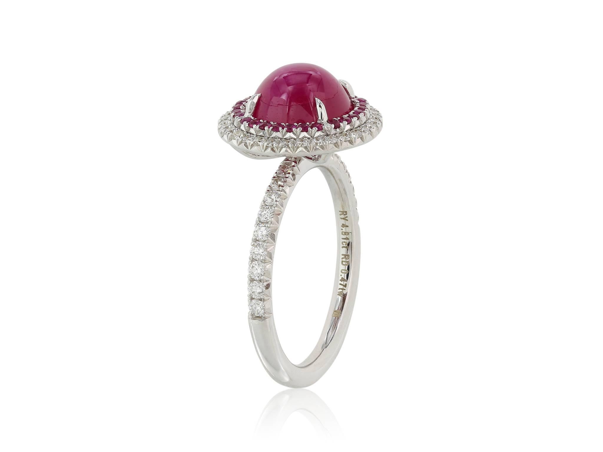 18 karat white gold ring consisting of 1 cabochon Burmese ruby weighing 4.81 carats surrounded by a halo of round rubies weighing .20 carats and shadowed by a row of round brilliant diamonds extending down the shank weighing .47 carats with a color