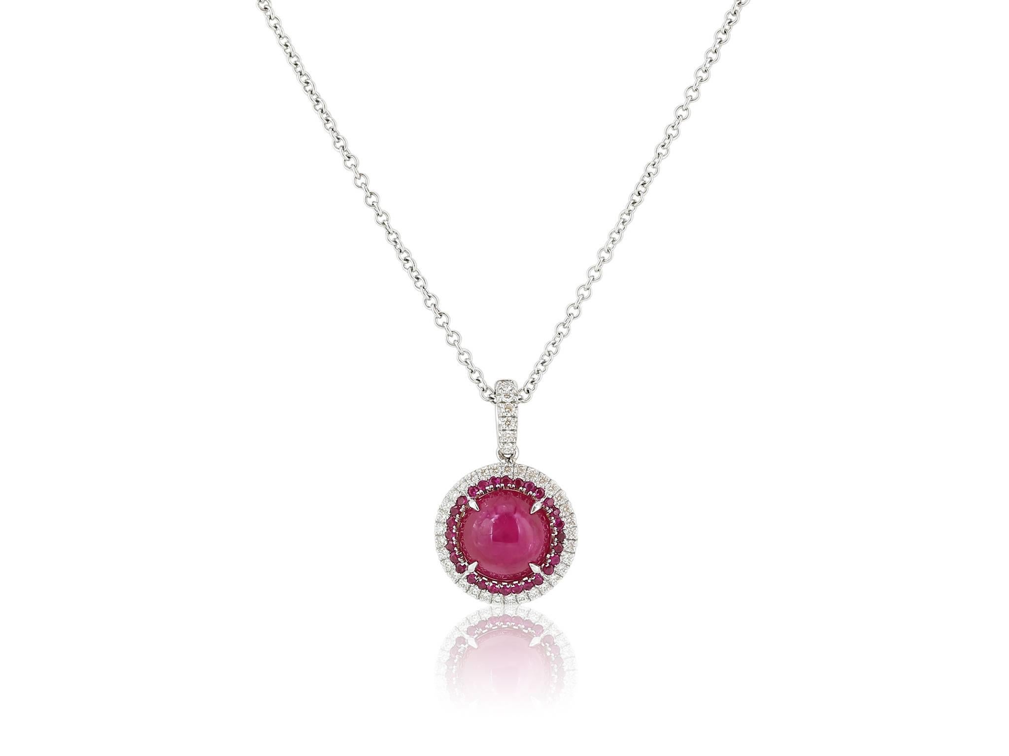 18 karat white gold pendant consisting of one round cabochon Burmese ruby weighing 4.12 carats surrounded by round rubies weighing .19 carats with a double halo and bail accented with round brilliant diamonds weighing .24 carats with a color and