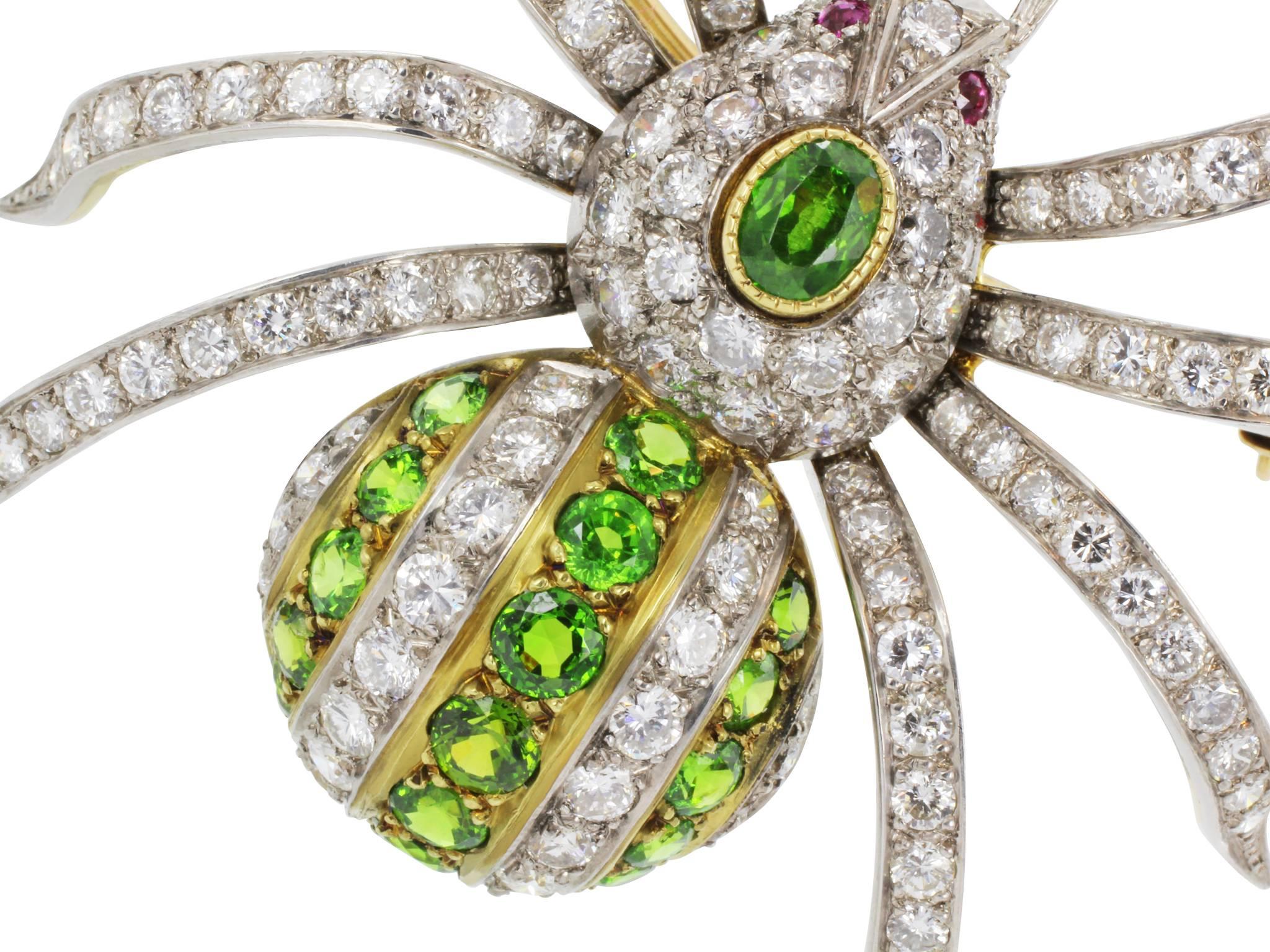 Platinum on 18 karat gold style spider pin set with brilliant cut diamonds weighing  approximately 5.50 cts and demantoid garnets and cabochon ruby eyes.