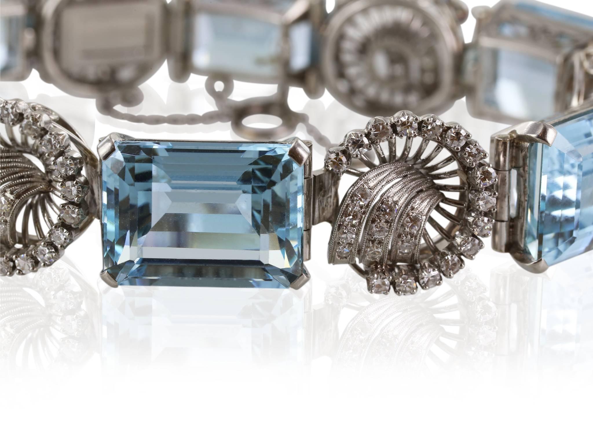 Platinum set Retro approximately 65 carat aquamarine bracelet featuring 6 emerald cut aquamarines and a swirl patter of round brilliant cut diamonds set between the aquamarines.