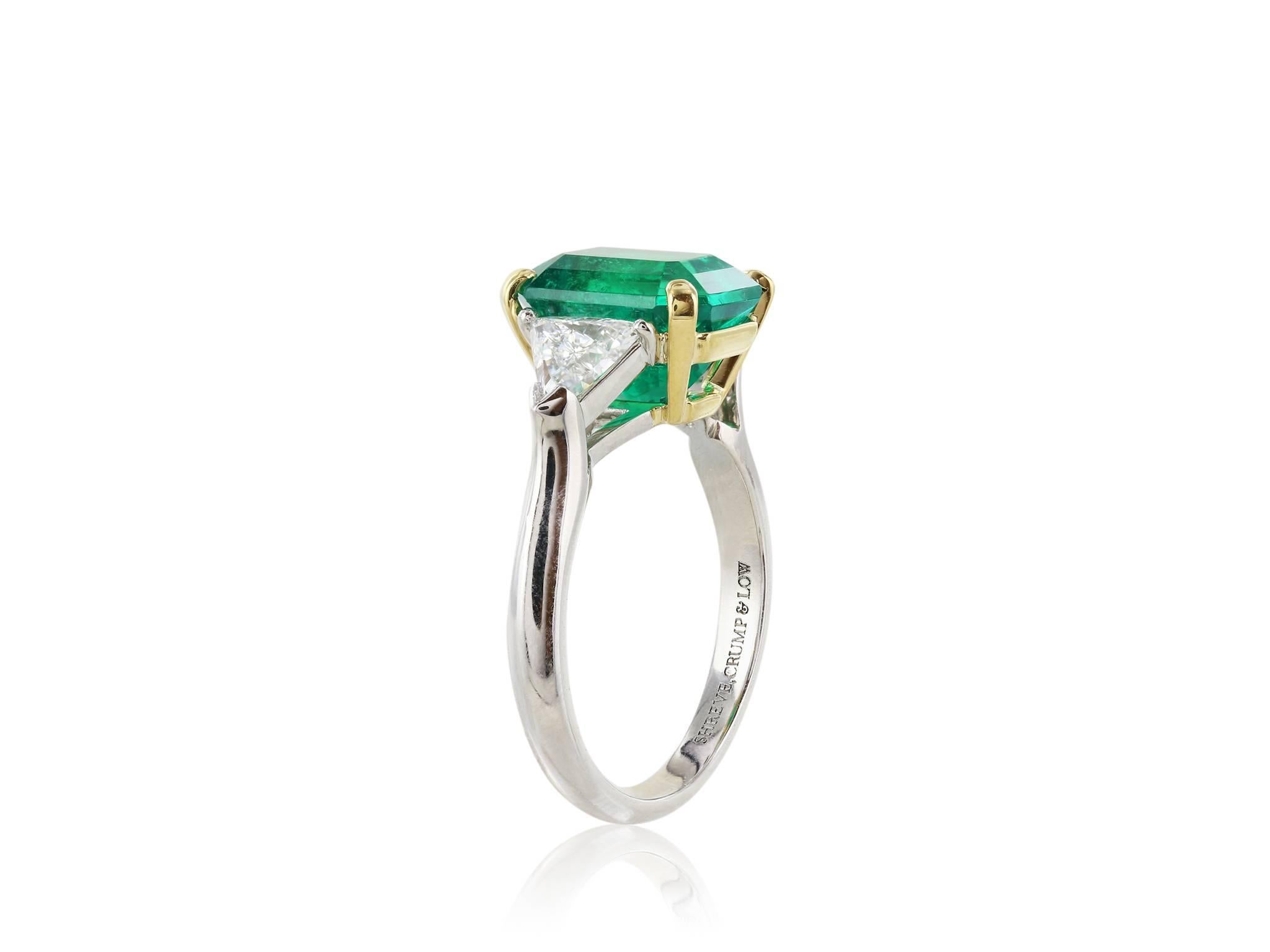 This beautiful Platinum and 18 karat yellow gold 3 stone ring featuring one 3.54 carat certified by C. Dunaigre Emerald cut Natural Colombian emerald.  The emerald is flanked by two trillium cut diamonds each weighing approximately .39 carats.