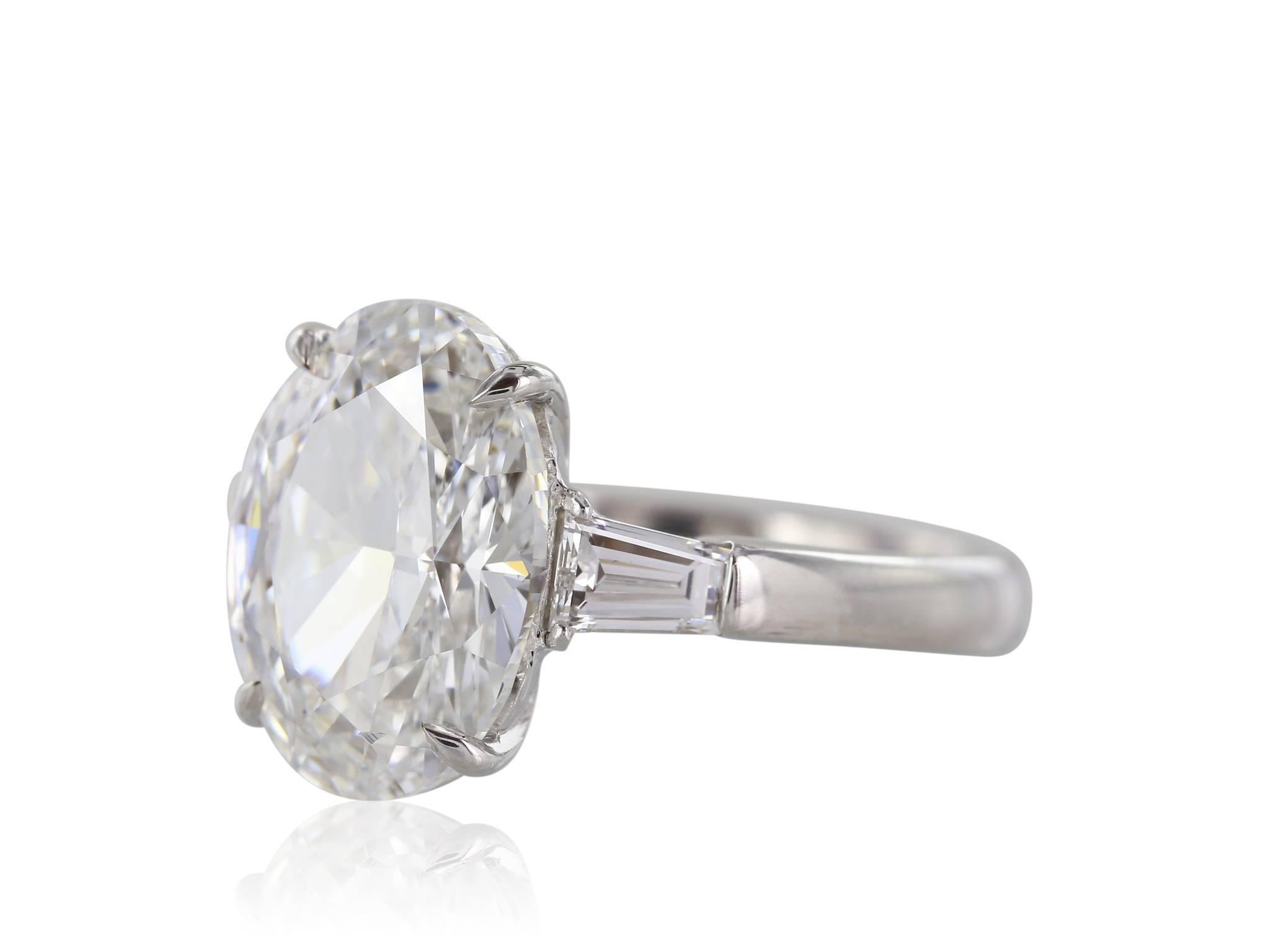 Platinum set three stone diamond ring featuring one GIA certified (#2171623454) 5.02 carat oval diamond with a color of F and a clarity of VS2.  The oval diamond is flanked by two tapered baguettes with a color of F, clarity of VS2 and combined