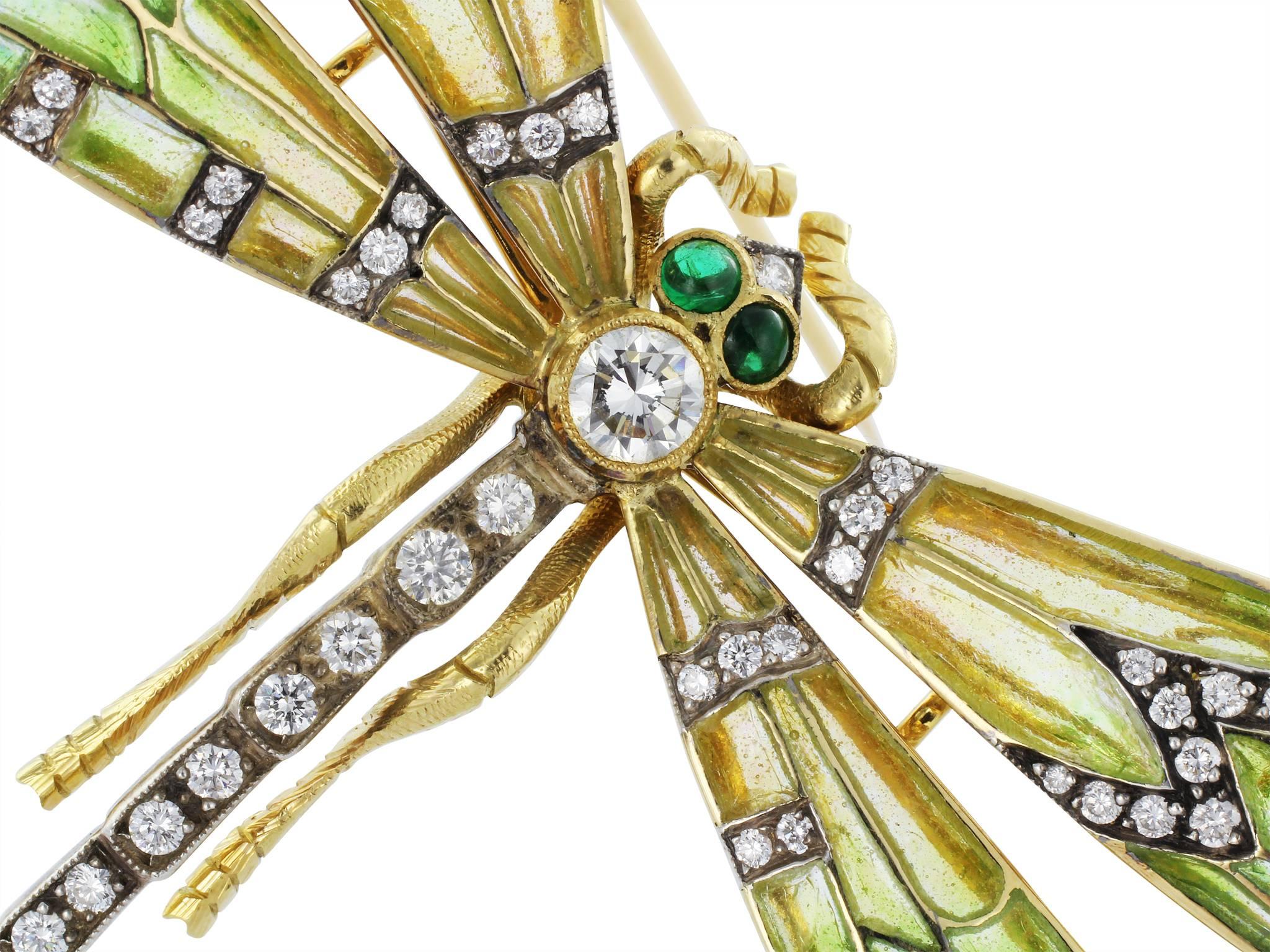18 karat yellow gold dragonfly pin with yellow, green and blue plique-a-jour wings, set with antique cut diamond accents set on the torso and on the wings and cabochon cut emerald eyes.