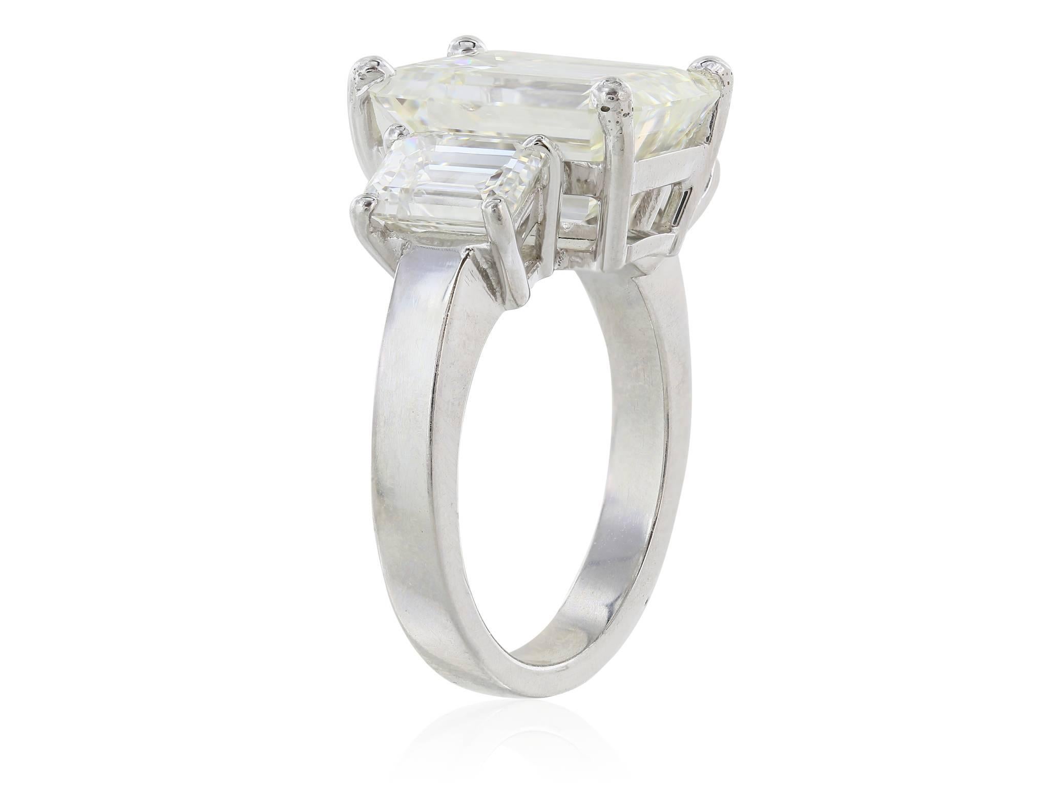 Platinum set three stone diamond ring featuring one GIA certified 6.36 carat emerald cut center stone flanked by two emerald cut side stones weighing approximately 1.90 carats total.  The diamonds have a color of J and a clarity of VS2. GIA cert