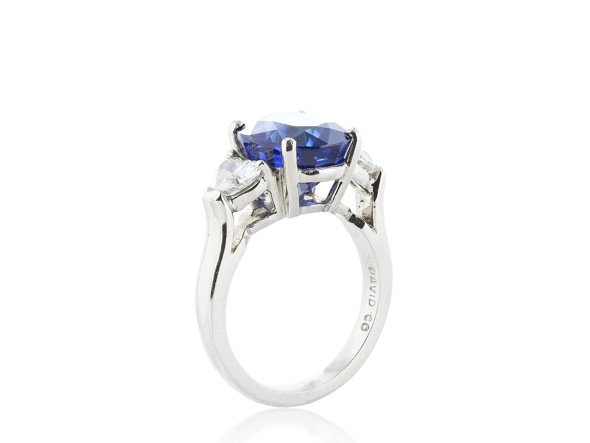 Platinum set three stone ring featuring one oval cut Ceylon sapphire weighing 6.52 carats.  The sapphire is flanked by two heart shaped diamonds with a combined carat weight of 1 carat, a color of F-G and a clarity of VS1.