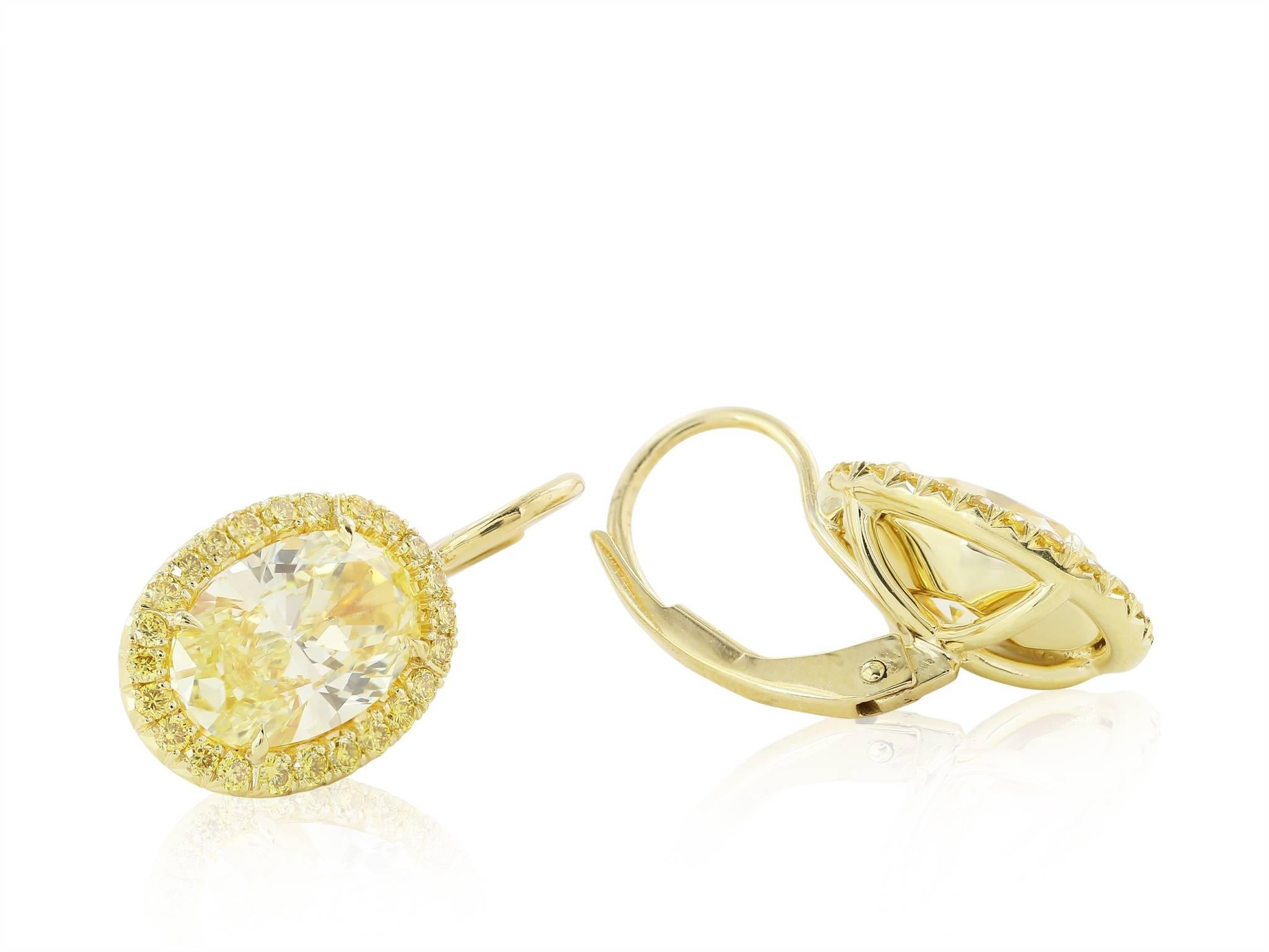 18 karat yellow gold custom made Natural Canary fancy yellow Oval diamond drop earrings. Consisting of two oval diamonds weighing 2.89 carats total weight surrounded by natural canary yellow diamonds 48 FC @ 0.32 carat yellow gold. GIA #2115225373,