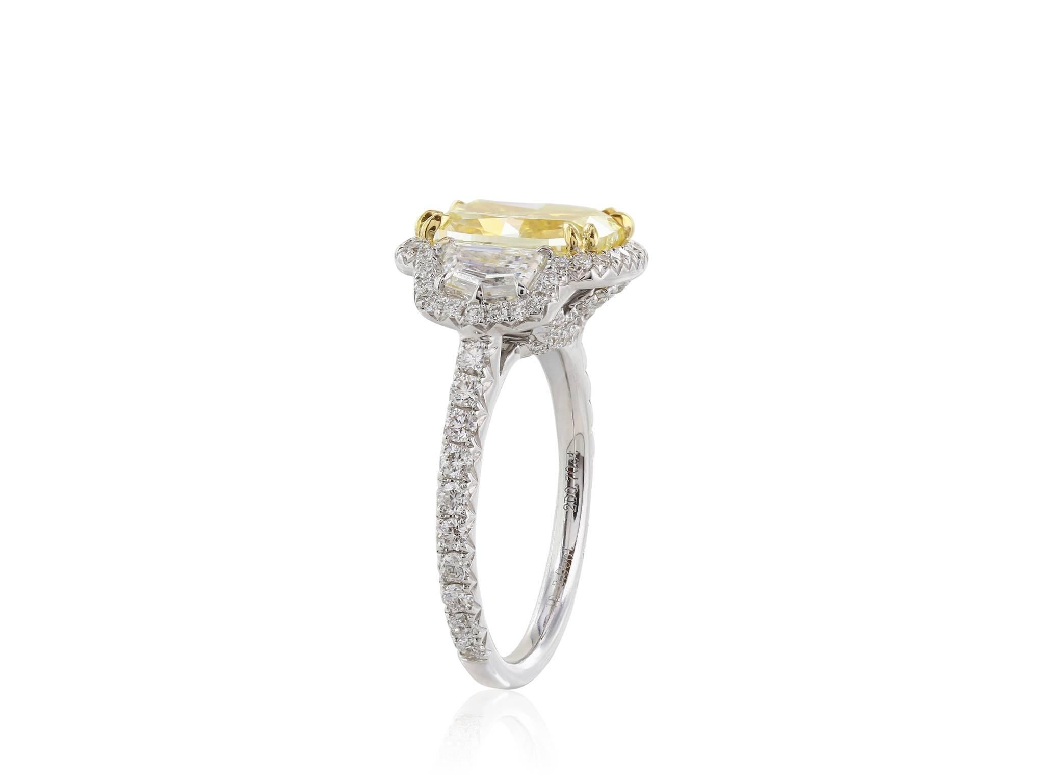18 Karat white gold 3 stone diamond halo ring featuring a GIA certified 3.05 carat Fancy Yellow +radiant cut center stone with a clarity of SI2+.  The center stone is flanked by two trapezoid .70 carat white diamonds with a color of G and a clarity