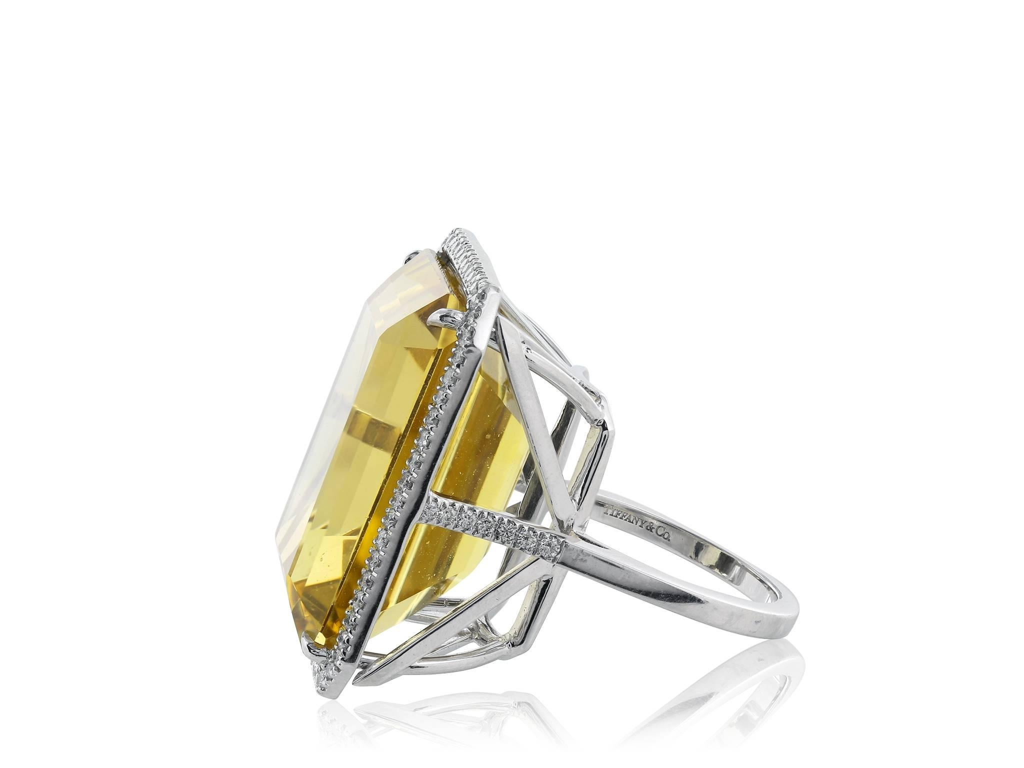 Platinum ring featuring 1 emerald cut citrine weighing approximately 30 carats surrounded by full cut diamonds. Singed Tiffany & Co