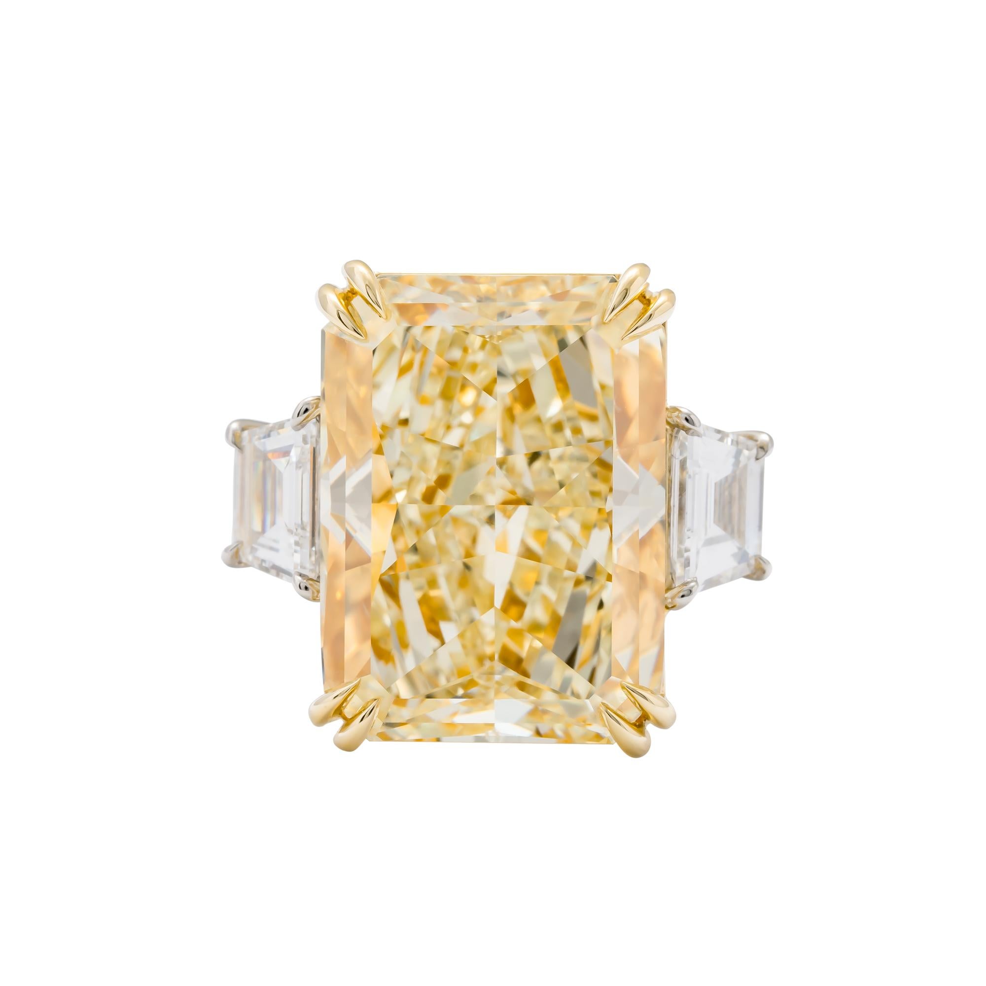 Platinum and 18 karat yellow gold 3 stone ring consisting of 1 radiant cut yellow diamond weighing 17.01 carats with color and clarity of FY/VS2 GIA #5182705391 flanked by 2 trapezoid diamonds weighing a total of 1.27 carats. D VVS2 Size 6.5
