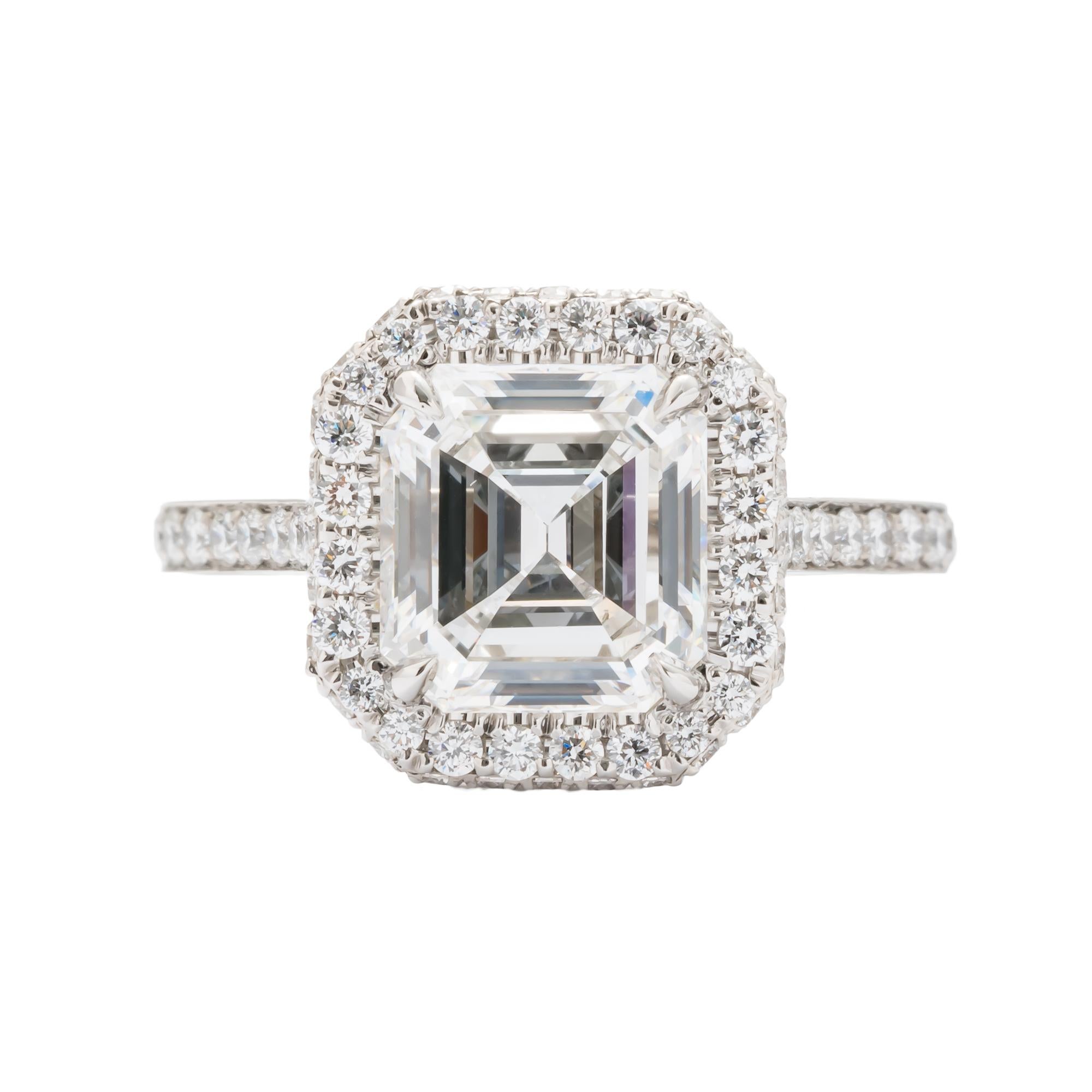 Platinum halo ring consisting of 1 emerald cut diamond weighing 2.74 carats with color and clarity of E/SI1 GIA#2193177533 surrounded by 88 round diamonds also set halfway down shank weighing a total of .84 carats. Size 6.5