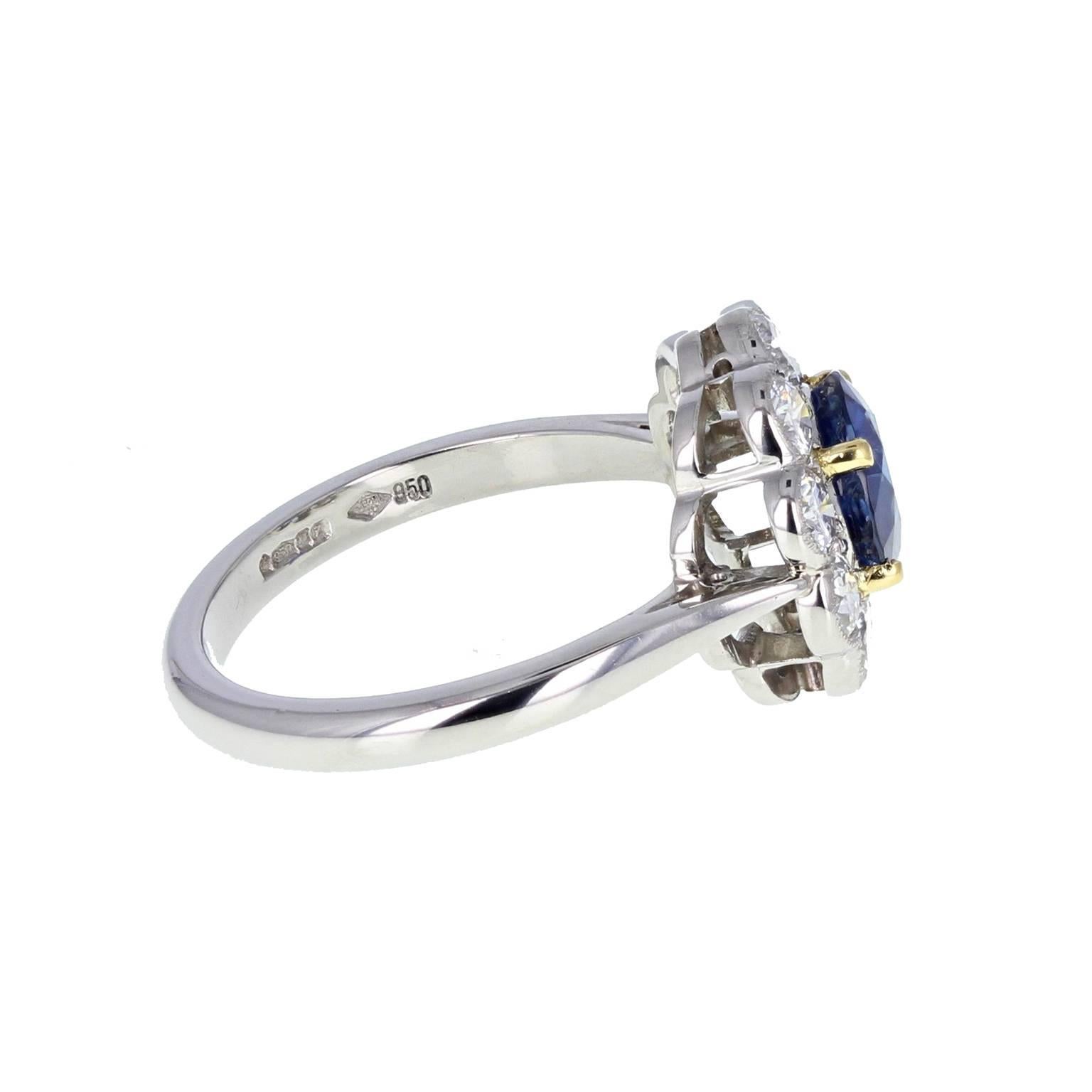 A wonderful, bright, lively and attractive modern ring set in platinum. The central round-cut sapphire exhibits the coveted deep royal blue. Mounted in four 18-carat gold claws and surrounded by 10 round, brilliant-cut diamonds, in a millegrain