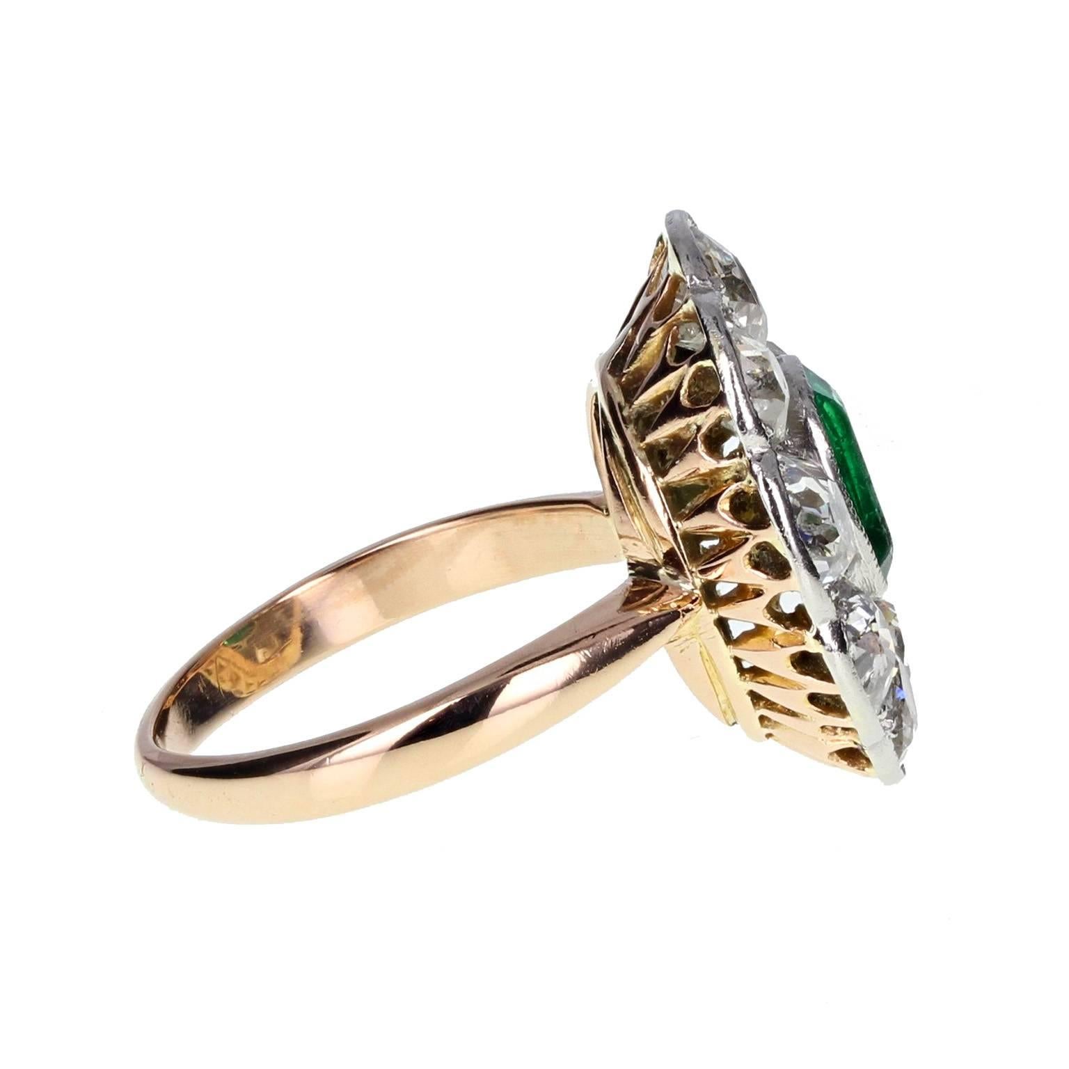 This wonderful Edwardian cluster ring features a central oval-cut lush green emerald, mounted in a mille-grain setting with pierced work, surrounded generously by old-cut diamonds. Rose gold shank and under setting. French assay marks to outer