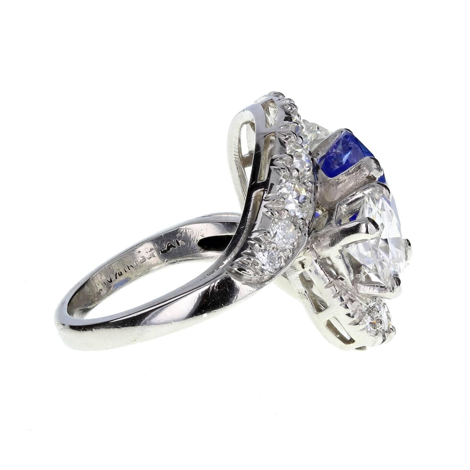 A fine quality sapphire and diamond fancy three stone ring. Central oval-cut sapphire of the beautiful velvety blue that is reminiscent of the highly prized Kashmir sapphires, flanked on either side by a single brilliant-cut diamond of approximately