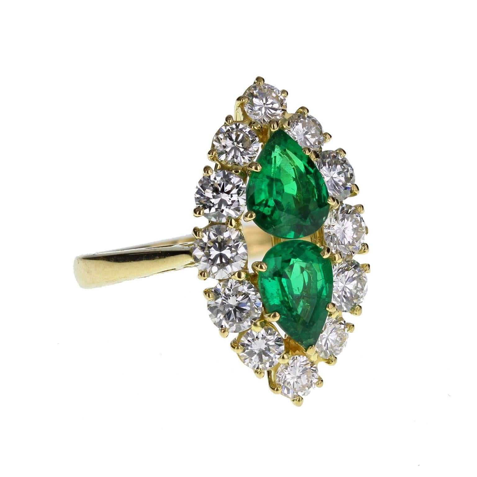 A fine and impressive cocktail ring featuring two deep, bottle-green pear shaped emeralds, surrounded generously with bright and lively diamonds to create a marquise-shaped cluster. Birmingham hallmark. A particularly fine quality ring at an