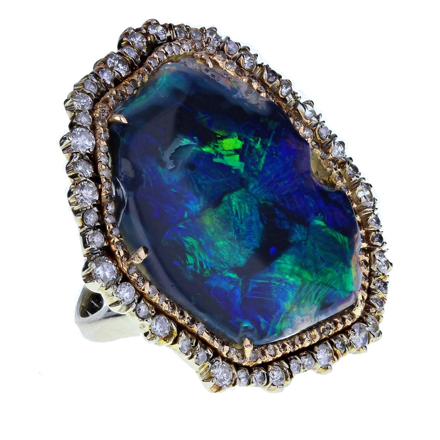 An abstract vintage ring featuring a exquisite black boulder opal that exhibits deep, iridescent peacock greens and blues. Surrounded by an organic double border of rose and white gold, pave set with various sized brilliant-cut diamonds. Plain white