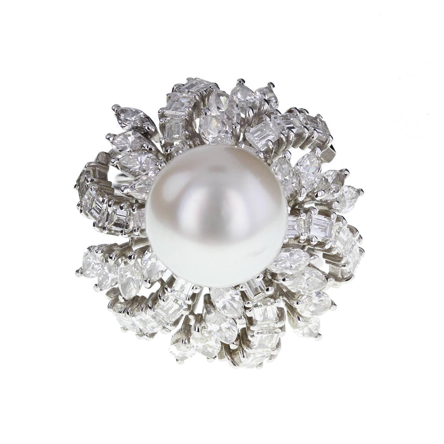 A beautiful cocktail ring centered with a large pearl of good lustre, surrounded by a 'skirt' of alternating rows of marquise and emerald-cut diamonds. Shank comprising five 'wires' of white gold, splitting at the shoulders. An impressive and