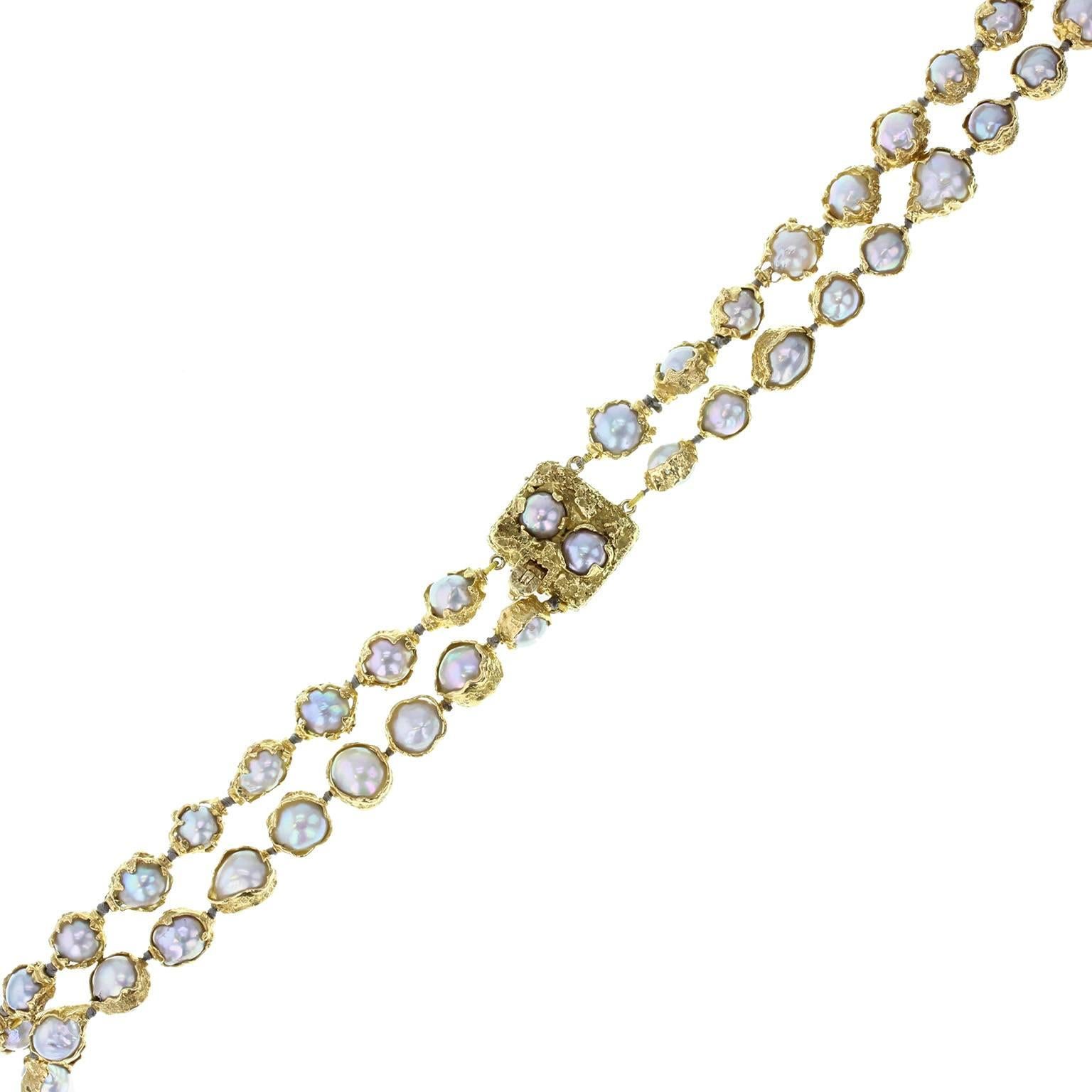 An exquisite, impressive and instantly recognisable necklace by Charles de Temple. Featuring a double row of grey pearls, each encapsulated in a stylised gold frame and strung and knotted on grey silk thread. Pearl set gold clasp. Signed 'CdeT' with